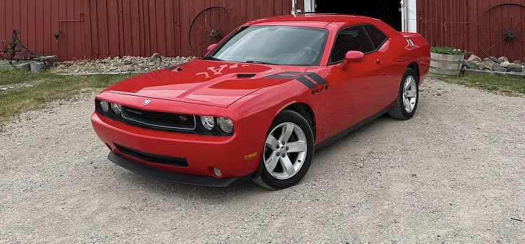 Red Dodge Challenger in front of barn
